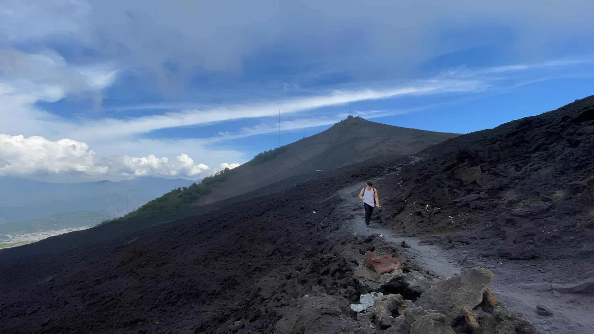 Black lava field sloping toward the Pacific coast under cloud on a Pacaya volcano day trip from Antigua, an alternative to Acatenango volcano tours in Guatemala